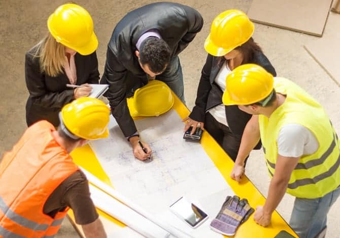 People in hard hats examine blueprints