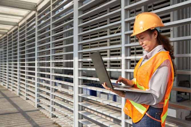 Person in hard hat with laptop on construction site