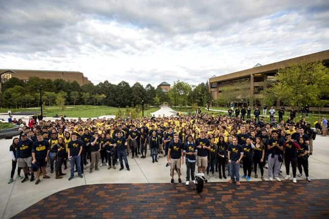 A group of people wearing matching t-shirts gather for a group photo.